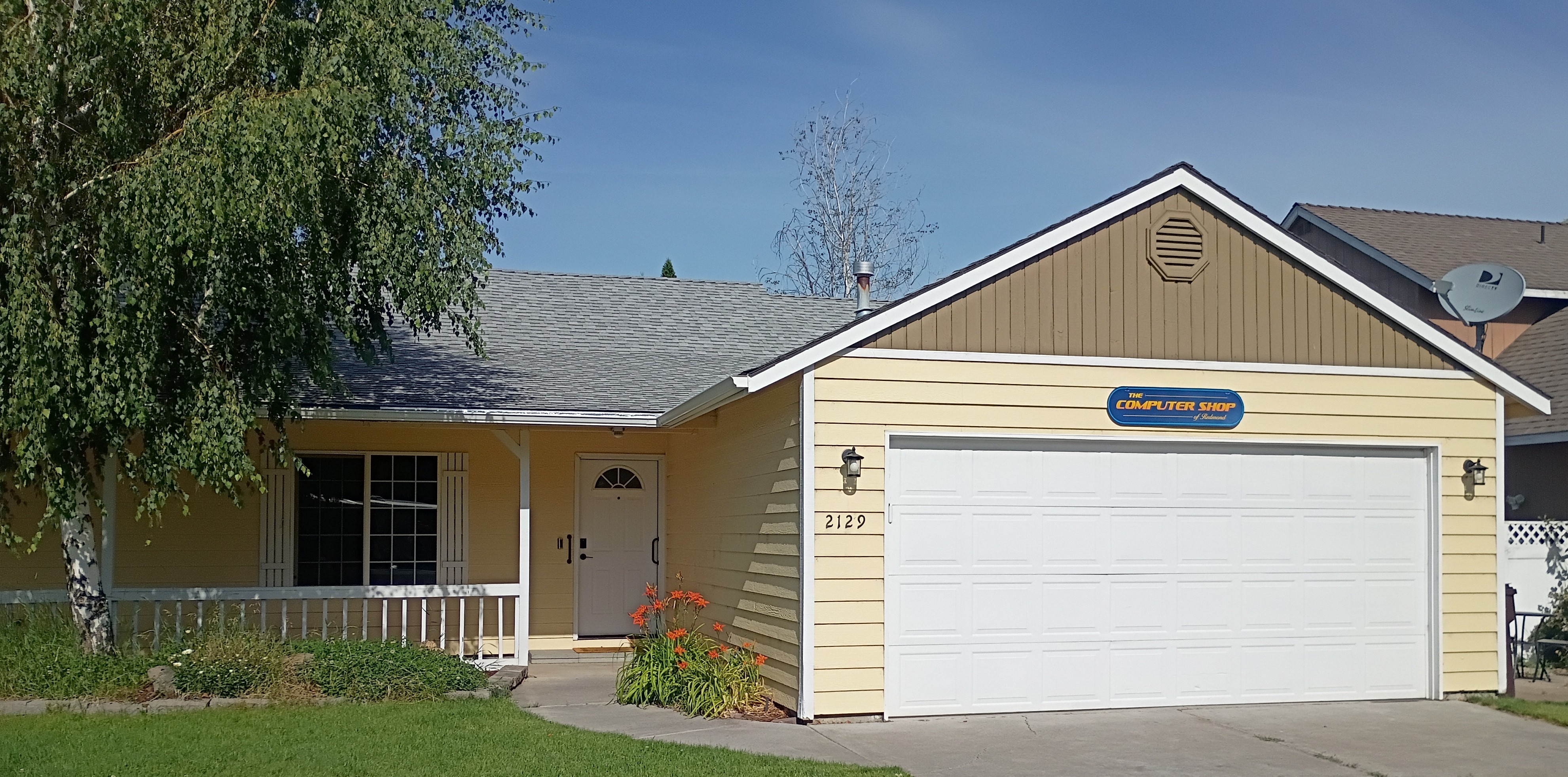 From street picture of the new location which is a yellow house with white trim, short white fence, grass yard, with a tree